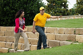 The Grounds Guys service professional walking with a customer along stone steps.