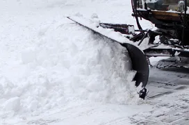 A snow plow pushing snow off a road.