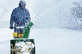 The Grounds Guys service professional using a snow blower during a snowstorm.