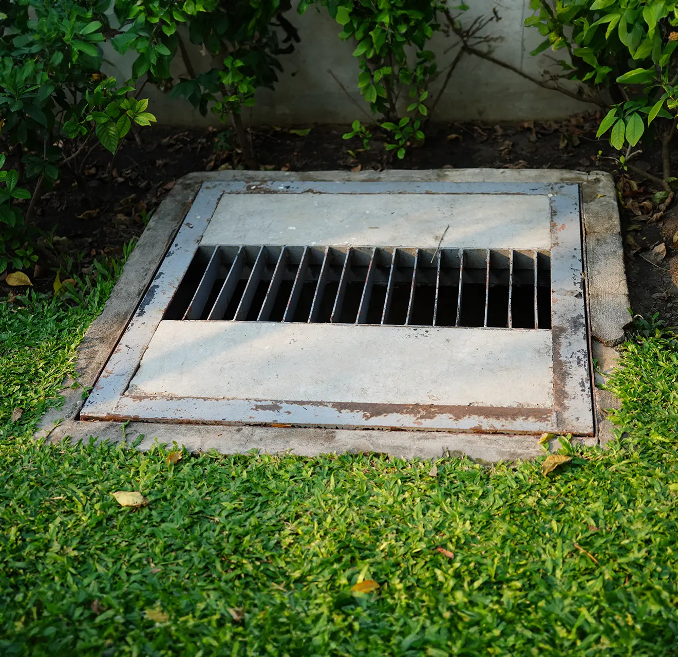 A cement and steel drain surrounded by grass.