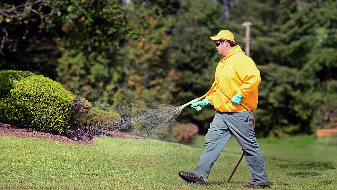 The Grounds Guys service professional spraying a lawn with pesticide.