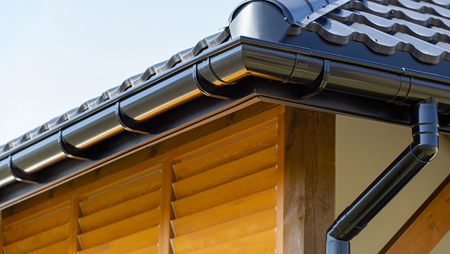 The black gutters, downspout, and roof of a commercial building.