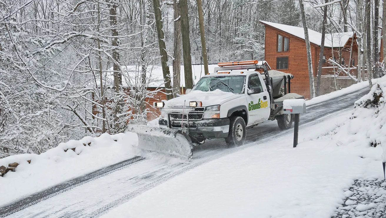 Grounds Guys plow truck pushing snow off driveway.