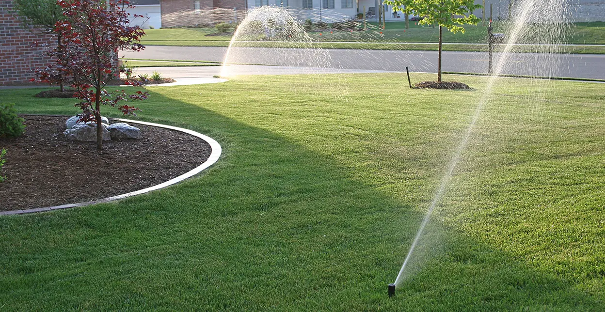 Sprinkler heads spraying water on a home's front lawn.