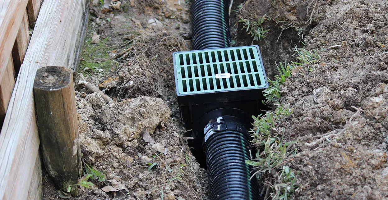 A drainpipe and basin installed in soil.