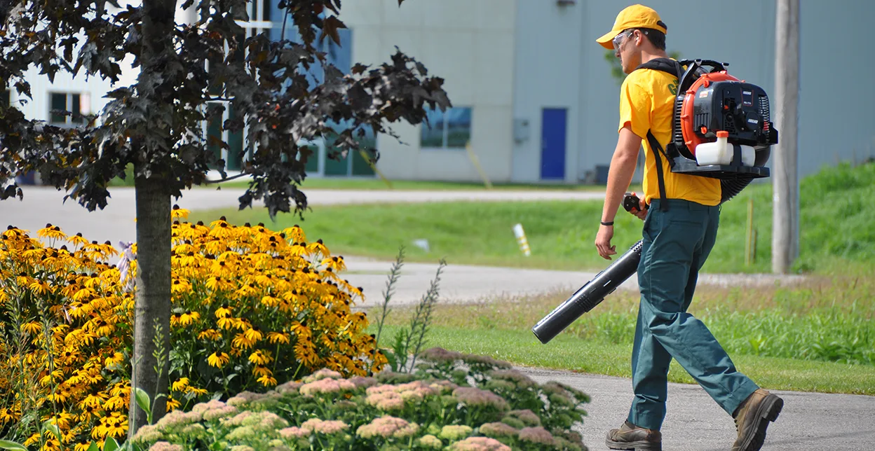 Grounds Guys Professional wearing a leaf blower. 