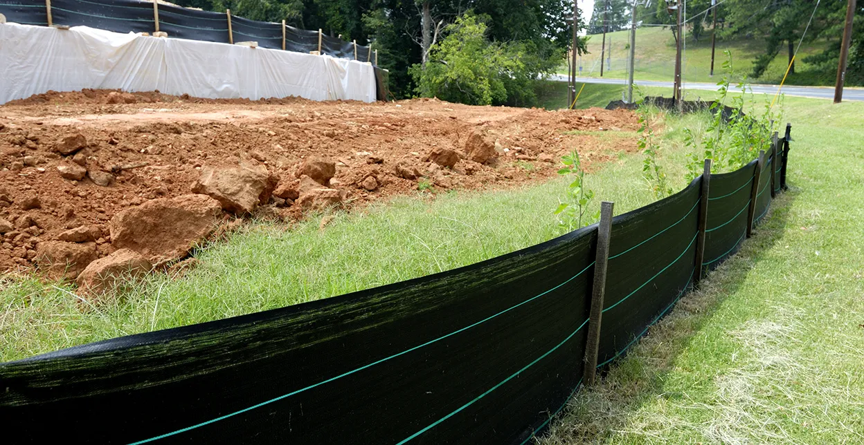 Silt fencing at a construction site with bare dirt from grading in the background.