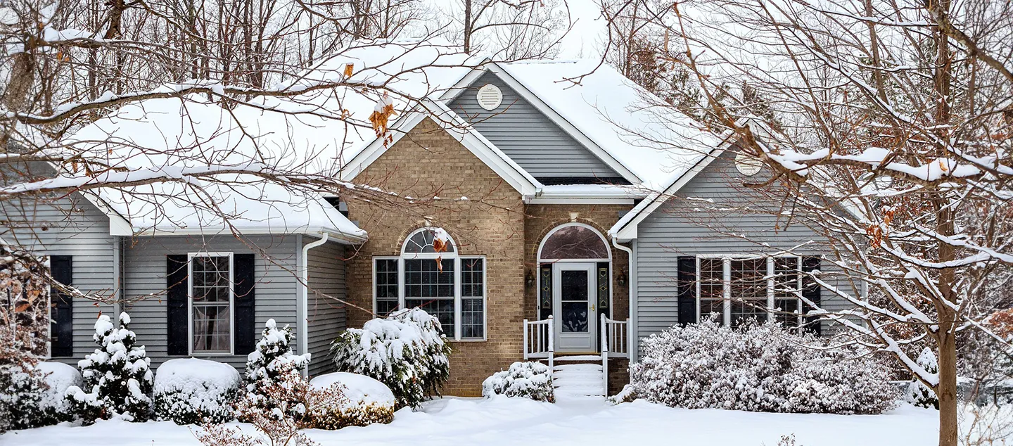 Freshly fallen snow covering the yard and roof of a single-family home.