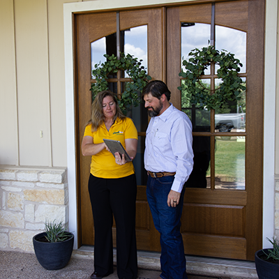 The Grounds Guys service professional showing a tablet to a client at their front door.