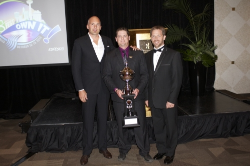 The Grounds Guys of Collingwood team holding Top Sales Award in front of stage.