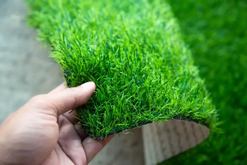 Hand holding piece of artificial grass