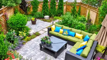 A beautiful small, urban backyard garden featuring a tumbled paver patio, flagstone steps, and a variety of trees, shrubs and perennials.