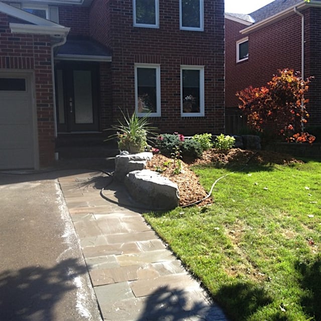 A garden with stone pathway plants in it.