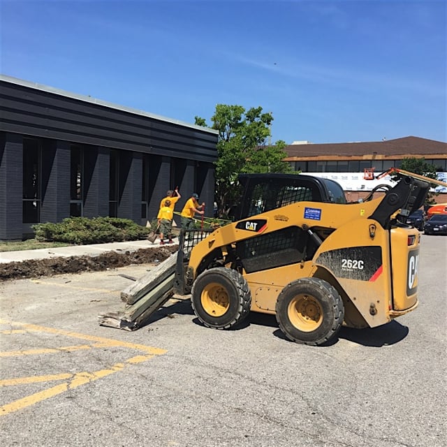 Ground guys working on a lawn with machinery.